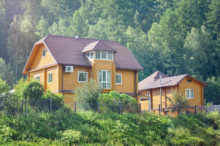 Beautiful wooden house with garden near green forest, ecological home in harmony with nature. Summer good sunny weather.の写真素材