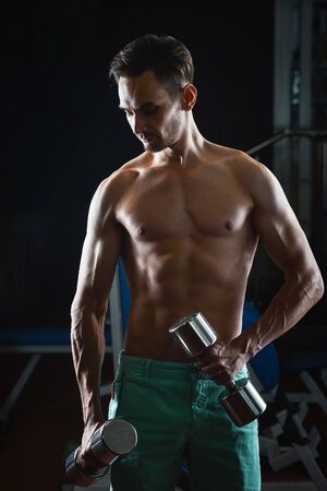 Muscular man with naked torso abs working out in gym with dumbellsの写真素材