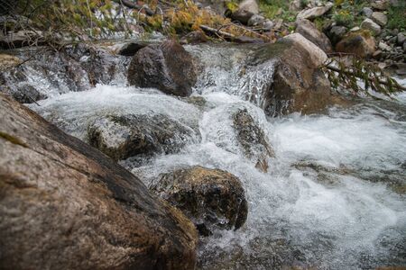 Strong flow of water in mountain river with splashes, close up shot.