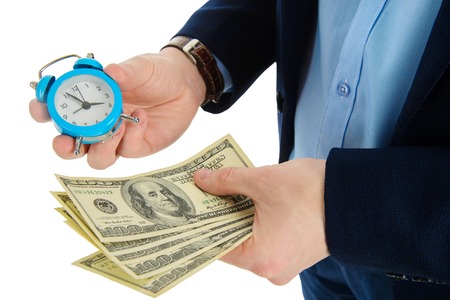 Close up of businessman holding a clock and one stack of cash in hand, time and money concept. Making right decision.の写真素材