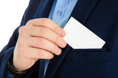 Businessman hand holding a business card over suit pocket, closeup. Isolated on white.の写真素材