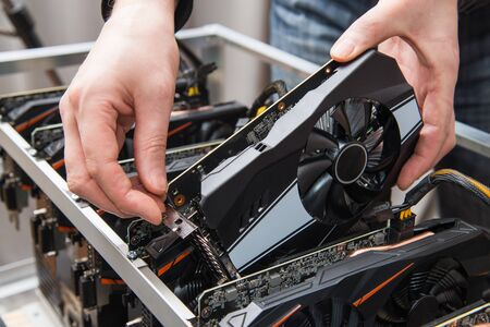 Mans hands connecting a new graphics card to mining farm. IT equipment. Cryptocurrency business.の写真素材