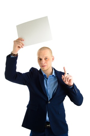 Handsome businessman in stylish suit holding empty sheet of paper over his head isolated on white backgroundの写真素材