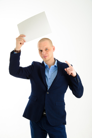 Handsome businessman in stylish suit holding empty sheet of paper over his head isolated on white backgroundの写真素材