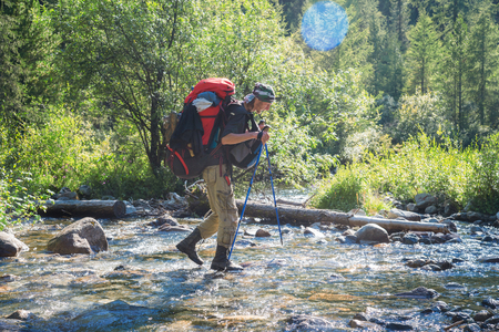 Hiker with backpack crossing mountain river. Hiking river crossing on the stones.の写真素材
