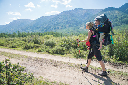 Woman Hiker trekking in mountains with child in backpack . Mother with baby boy travelling in summer sunny day.の写真素材
