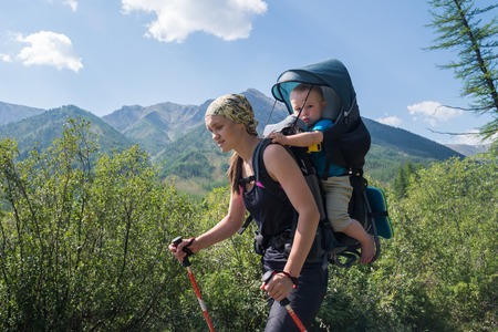 Woman Hiker trekking in mountains with child in backpack . Mother with baby boy travelling in summer sunny day.の写真素材