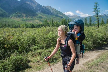 Woman Hiker trekking in mountains with child in backpack . Mother with baby boy travelling in summer sunny day.の写真素材