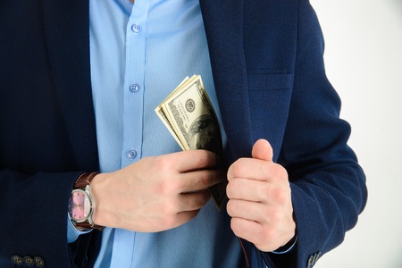 Businessman put money in his suit pocket - closeupの写真素材