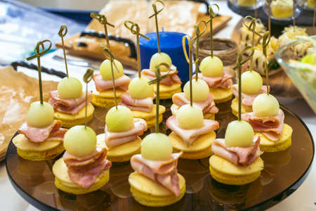 Beautiful decorated catering banquet table with different food snacks and appetizers. Canape plate with grape, cheese, bacon and crusty breadの写真素材
