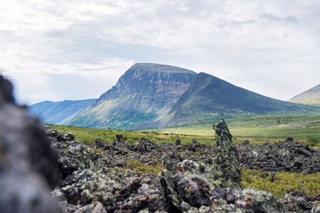 Frozen lava field in volcano valley with old Vulcan at background. Scenic landscape, Russia, Siberia.の写真素材