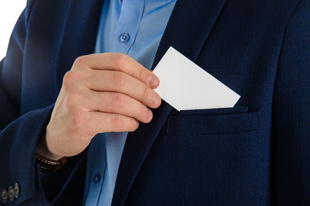 Businessman hand holding a business card over suit pocket, closeup. Isolated on white.の写真素材