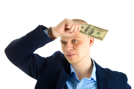 Thoughtful businessman in suit on white background holding cash, us dollars, worried about financial problems.の写真素材