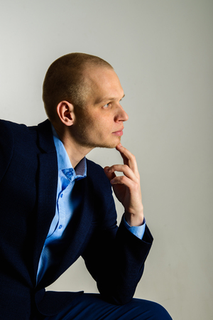 Closeup portrait of thoughtful man in suit onlight grey backgroundの写真素材