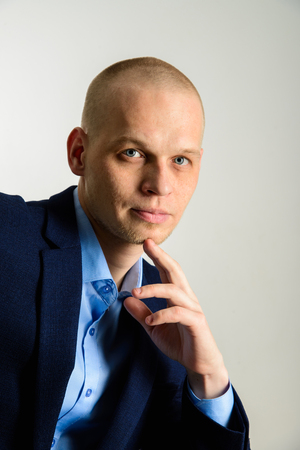 Closeup portrait of thoughtful man in suit onlight grey backgroundの写真素材