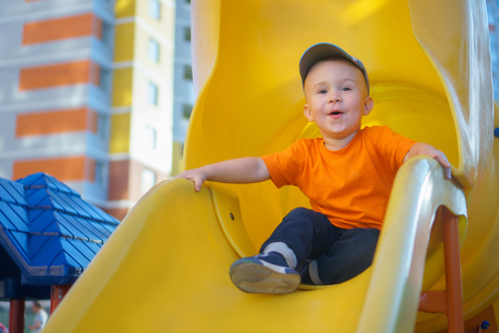 Little boy having fun on a playground outdoors in summer. Playful toddler on a slide.の写真素材