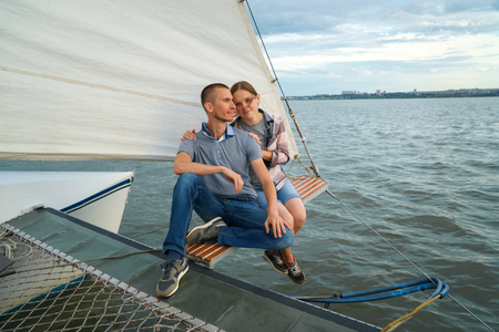 Young Couple hugging, sitting on boat enjoying summer dayの写真素材