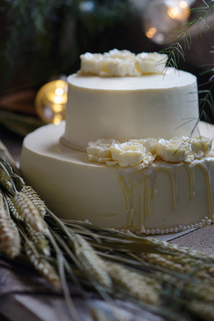 Wedding cream cake on rustic background. Beautiful Gourmet tart decorated with white roses and ears of wheat.の写真素材