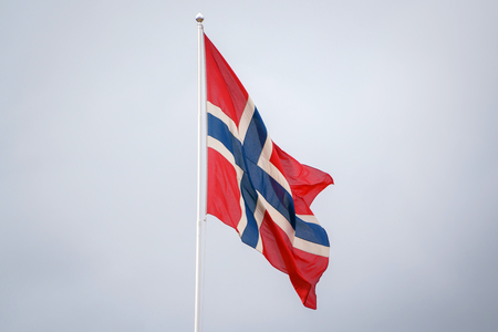 Norwegian flag waving on blue clear sky backgroundの写真素材