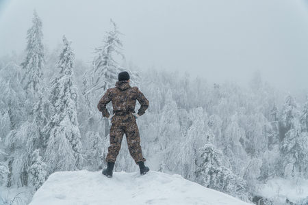 Man hiker standing back on rock in winter mountain landscape, successの写真素材