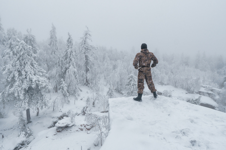 Man hiker standing back on rock in winter mountain landscape, successの写真素材