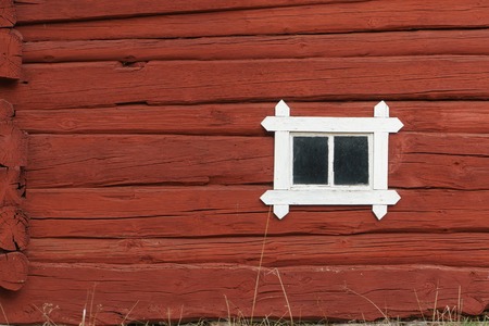 Old Wooden red log wall with small window, traditional in Scandinavia.の写真素材