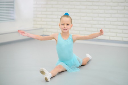 Little ballerina in blue dress and pointe shoes is dancing in ballet school. Cute girl in dance class.の写真素材