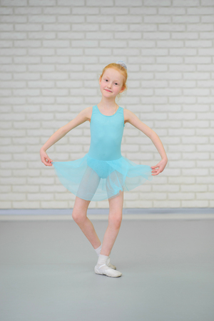 Cute little ballerina in blue dress dancing at ballet class.の写真素材