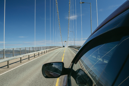 View from side of car, driving on modern bridge at sunny day with beautiful blue sky at background.の写真素材