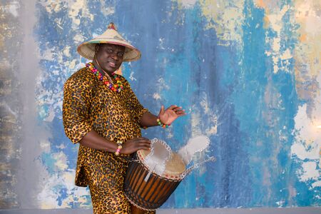 Handsome african drummer weared in traditional costume playing on djembe drumの写真素材