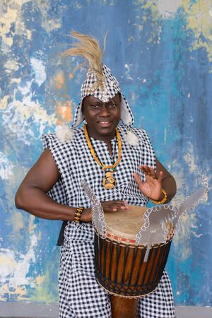 African artist in traditional clothes playing djembe drumの写真素材