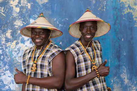 Two cheerful african men in traditional costumes showing thumbs upの写真素材