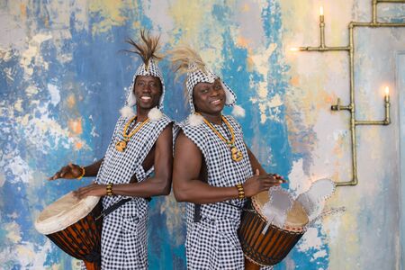 A group of people in traditional african costumes playing jembe drumsの写真素材