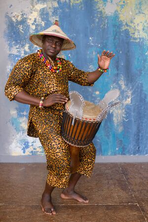 Handsome african drummer weared in traditional costume playing on djembe drumの写真素材
