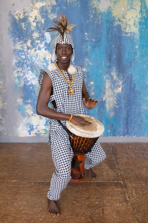 African artist in traditional clothes playing djembe drumの写真素材