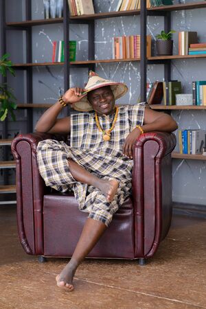 Happy Handsome african man in traditional clothes sitting on chairの写真素材