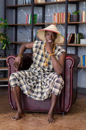 Happy Handsome african man in traditional clothes sitting on chairの写真素材