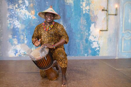 Handsome african drummer weared in traditional costume playing on djembe drumの写真素材