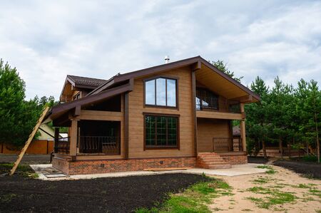 Facade of new house under construction, unfinished wooden home painted with brown natural color.の写真素材