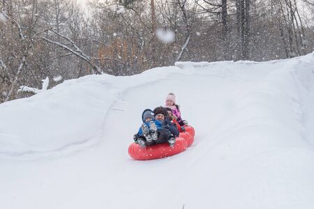 Russia, Izhevsk - January 7, 2020: People sliding down on snow tubes. Winter, leisure and sportのeditorial素材