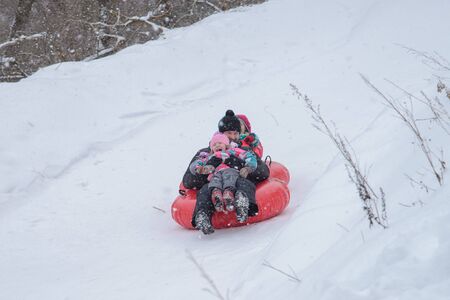Russia, Izhevsk - January 7, 2020: People sliding down on snow tubes. Winter, leisure and sportのeditorial素材