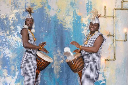 A group of people in traditional african costumes playing jembe drumsの写真素材