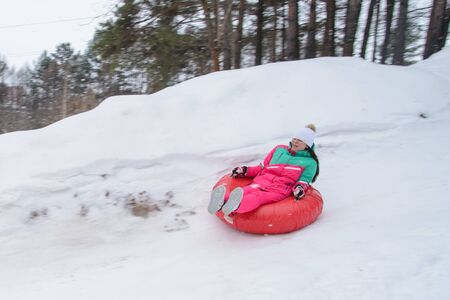 Russia, Izhevsk - January 7, 2020: People sliding down on snow tubes. Winter, leisure and sportのeditorial素材