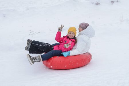 Russia, Izhevsk - January 7, 2020: People sliding down on snow tubes. Winter, leisure and sportのeditorial素材