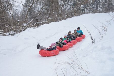 Russia, Izhevsk - January 7, 2020: People sliding down on snow tubes. Winter, leisure and sportのeditorial素材