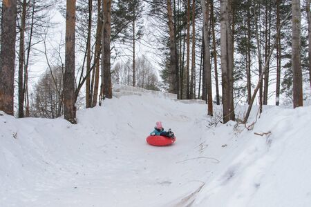 Russia, Izhevsk - January 7, 2020: People sliding down on snow tubes. Winter, leisure and sportのeditorial素材