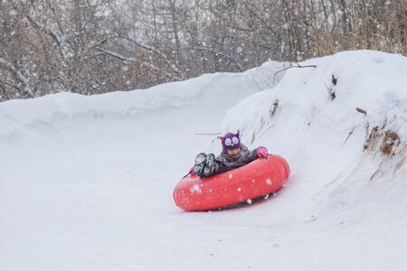 Russia, Izhevsk - January 7, 2020: People sliding down on snow tubes. Winter, leisure and sportのeditorial素材