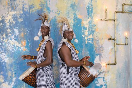 A group of people in traditional african costumes playing jembe drumsの写真素材