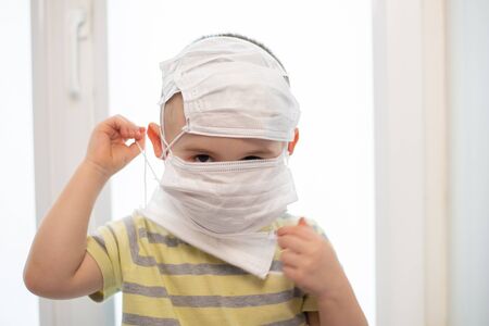 Toddler boy in wearing many medicine masks, quarantine at home, virus protectionの写真素材