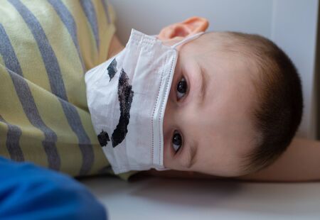 Unhappy boy in medicine mask, closeup portrait, quarantine at home, virus protectionの写真素材